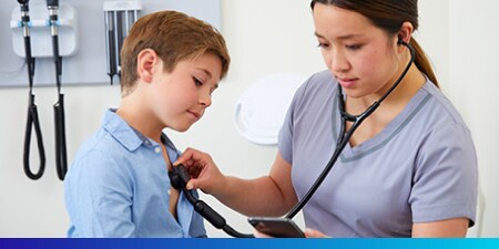 スマートフォンのアプリを少年と見ながら少年を聴診している医療従事者
